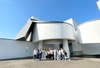 A group of people standing in front of a modern white building with a unique architectural design.