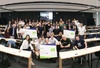A group of people posing in a classroom environment, holding certificates and smiling at the camera.