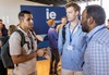 A group of three men engaged in conversation at an event.