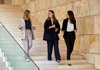 Three women are walking together down a staircase in a modern building.