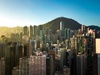A cityscape showing numerous high-rise buildings with a mountain in the background during sunset.
