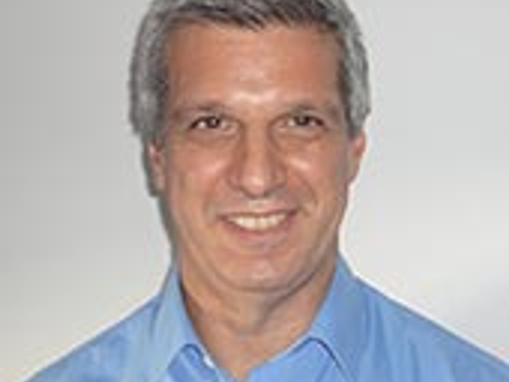 A smiling man in a blue shirt against a white background.