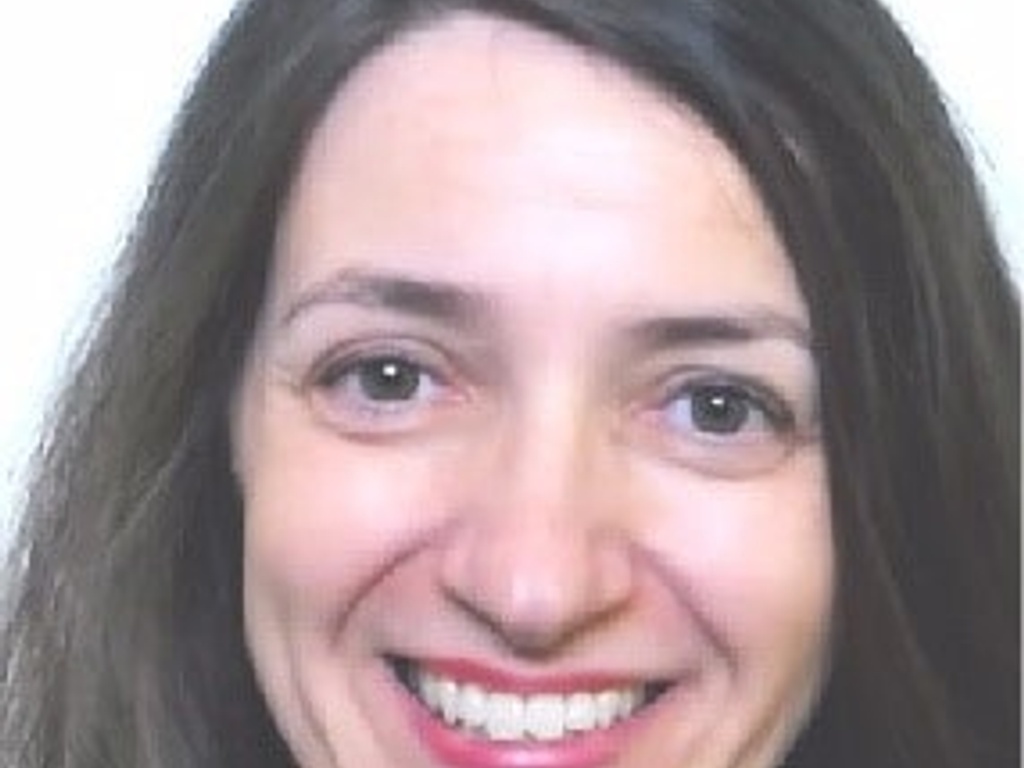 A portrait of a smiling woman with long dark hair.