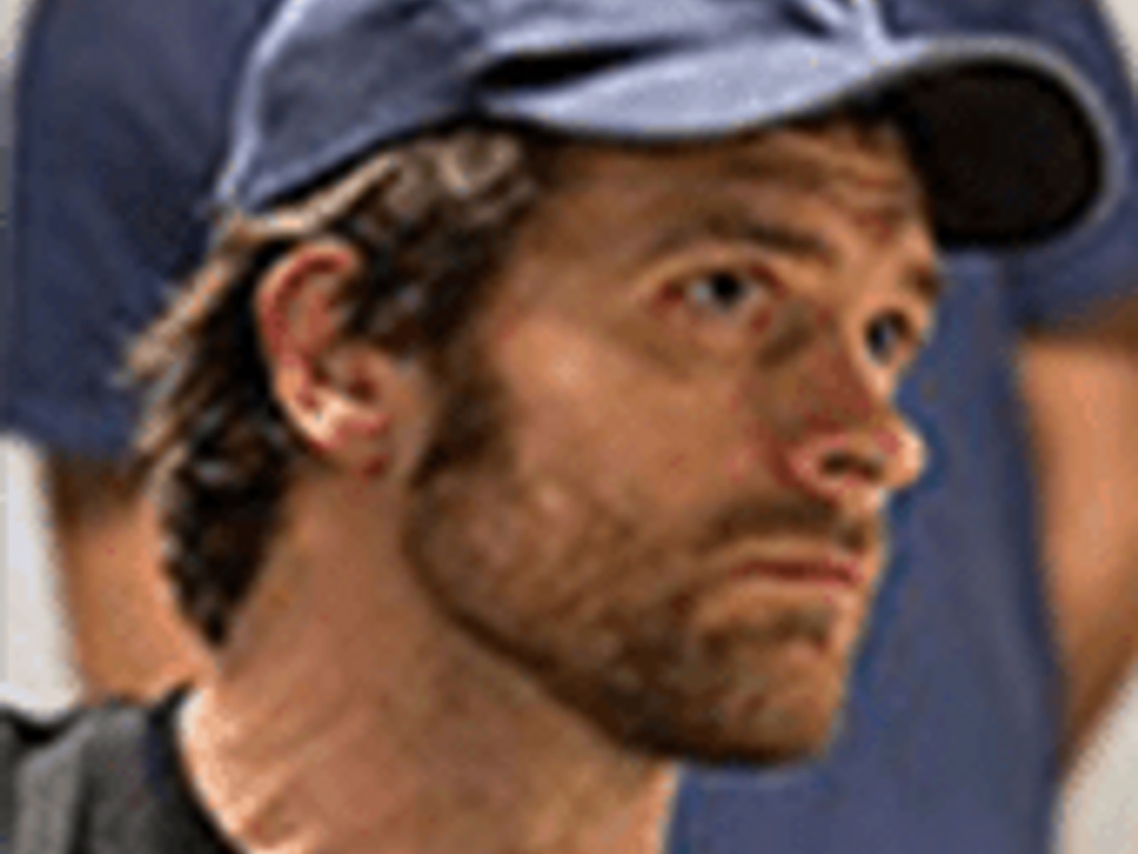 A man wearing a blue cap looking to the side with a thoughtful expression.