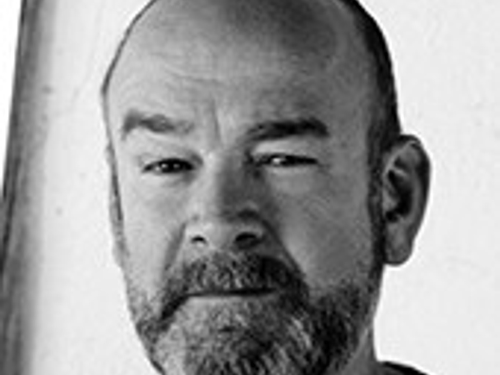 Black and white portrait of a middle-aged man with a beard, looking directly at the camera