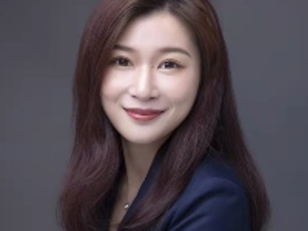 A professional portrait of a smiling woman with long hair in a dark suit.