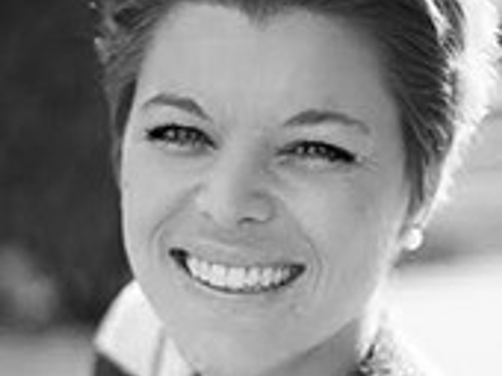 Black and white portrait of a smiling woman with short hair looking at the camera.