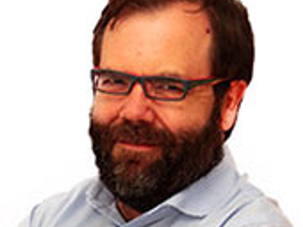 A middle-aged man with a beard, wearing glasses and a blue shirt, smiling at the camera.