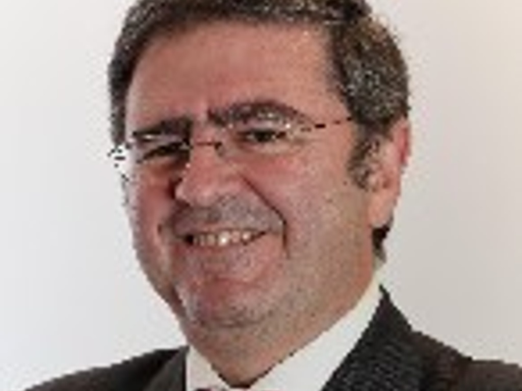 A professional portrait of a smiling man wearing a suit and tie.