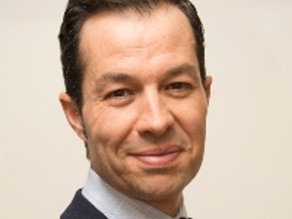 A portrait of a smiling man wearing a suit and a red tie.