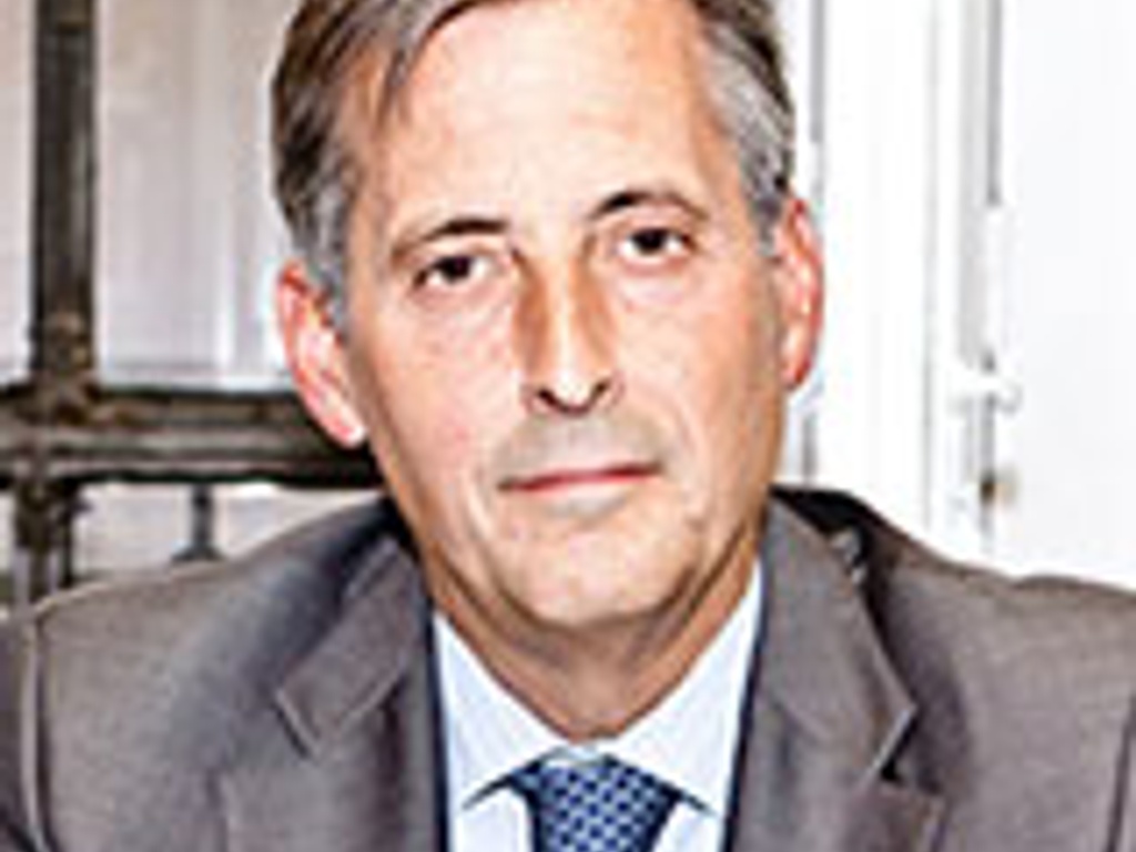 A mature man in a suit and tie sitting in an office environment.