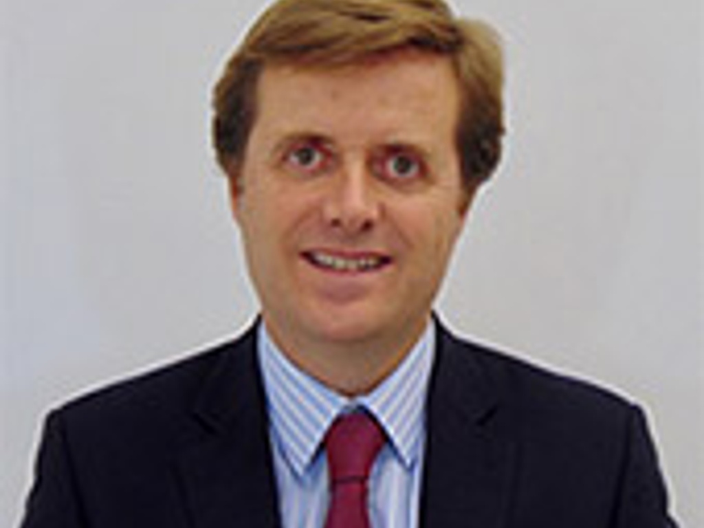 A portrait of a man in a suit with a striped tie and blue shirt, smiling at the camera.