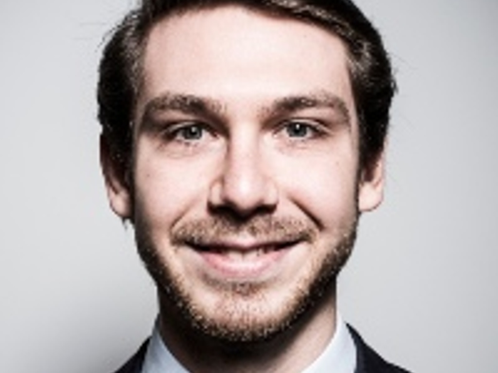 A portrait of a smiling man wearing a suit and tie.