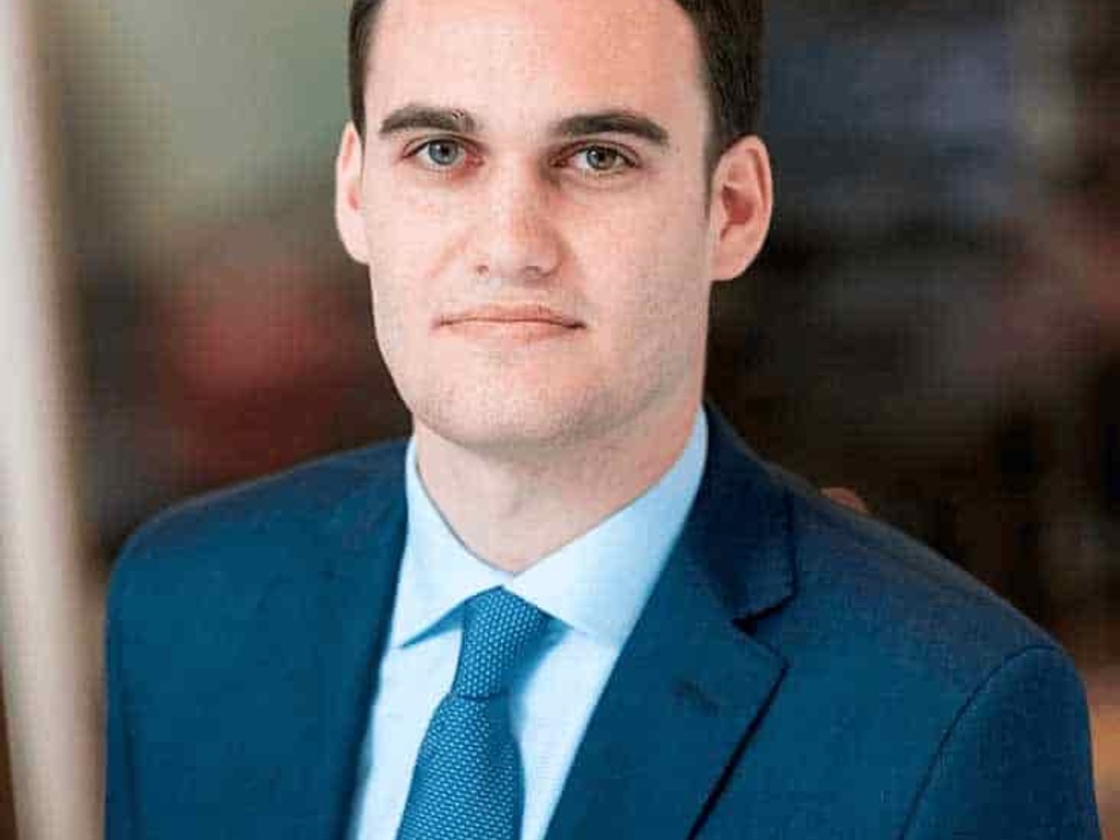 A professional portrait of a man in a blue suit and tie.