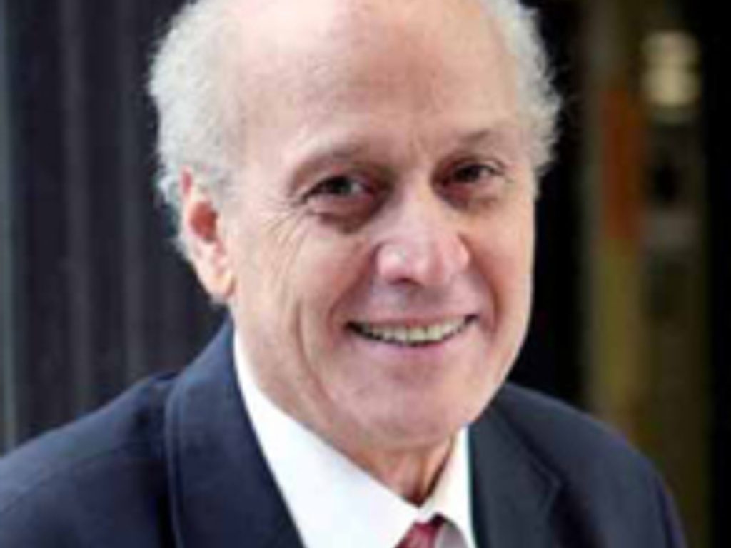 A portrait of an elderly man with a joyful expression, wearing a suit and a red tie.