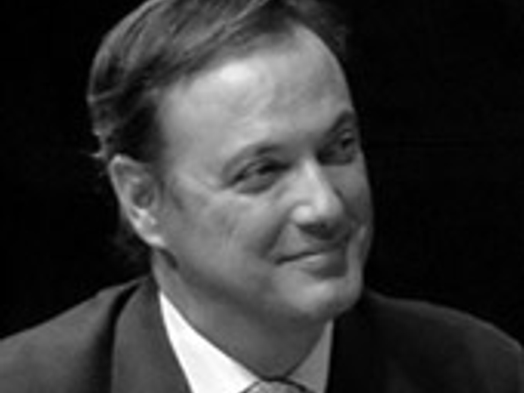 Black and white photo of a smiling man in a suit.