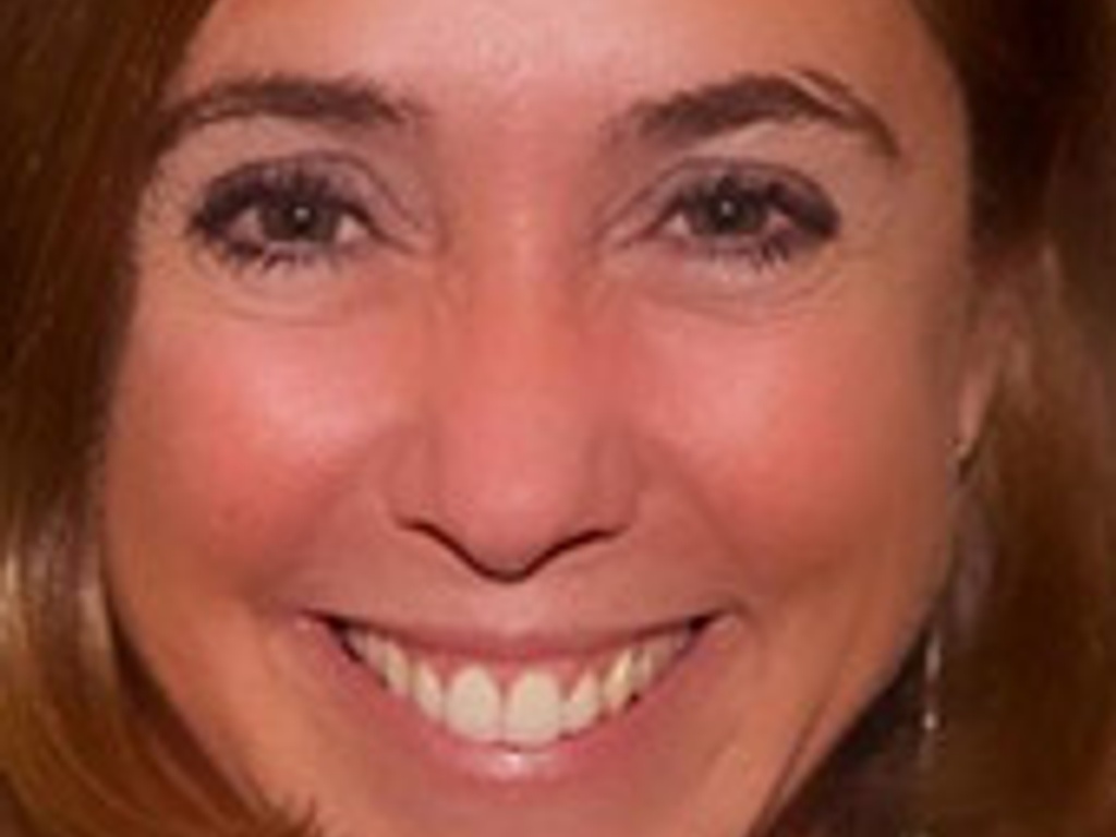 Close-up portrait of a smiling woman with brown hair.