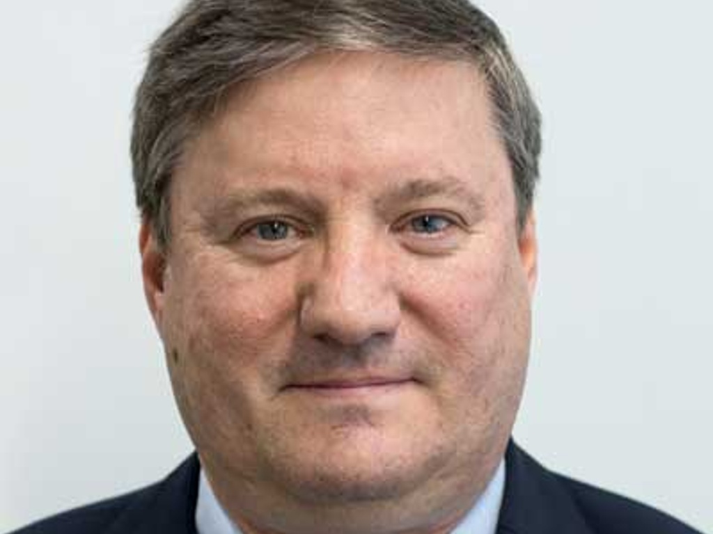 A portrait of a middle-aged man with a neutral expression, wearing a suit and tie.