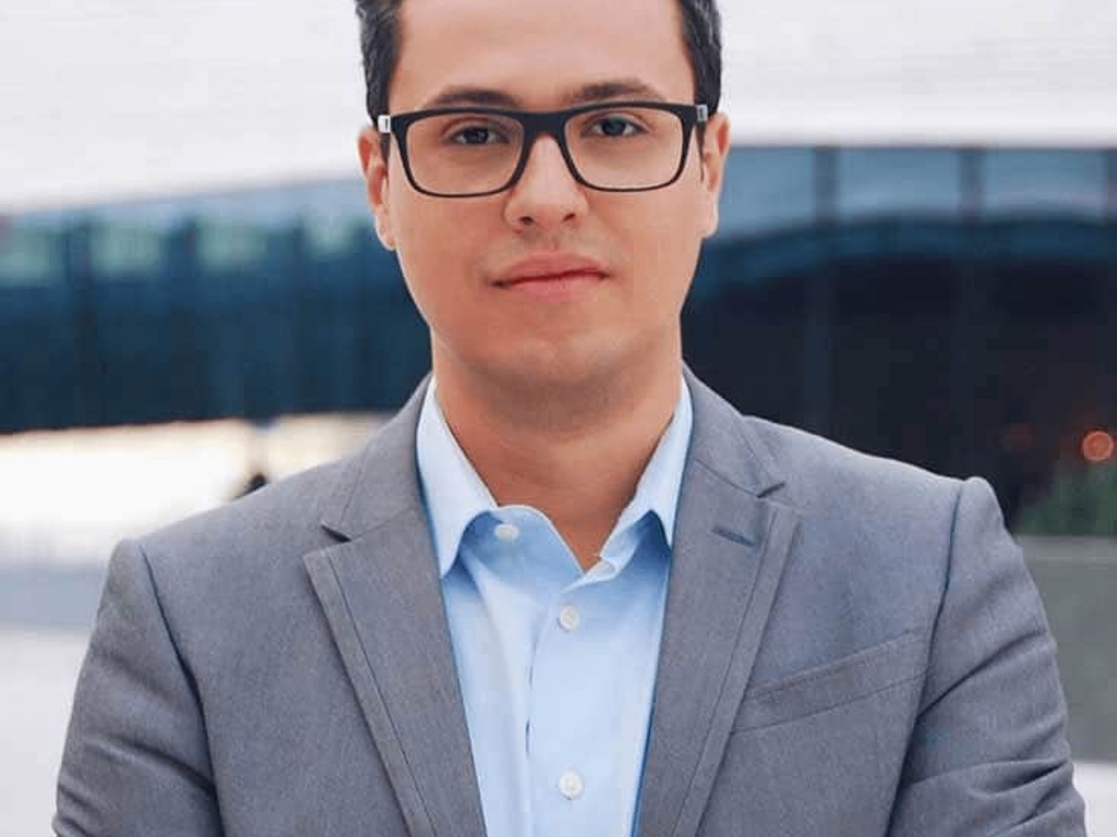 A professional looking young man in a business suit standing in front of a modern building.