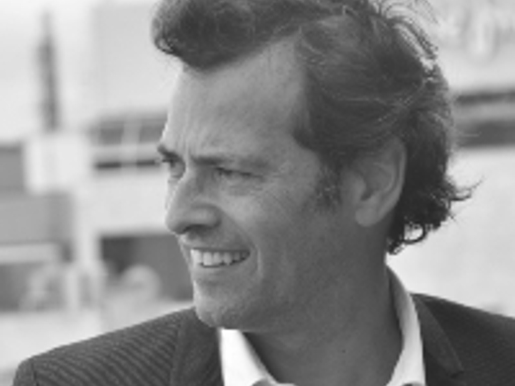 A black and white photo of a smiling man in a suit looking away from the camera.