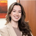 A professional woman with long brown hair smiling in a corporate office environment.