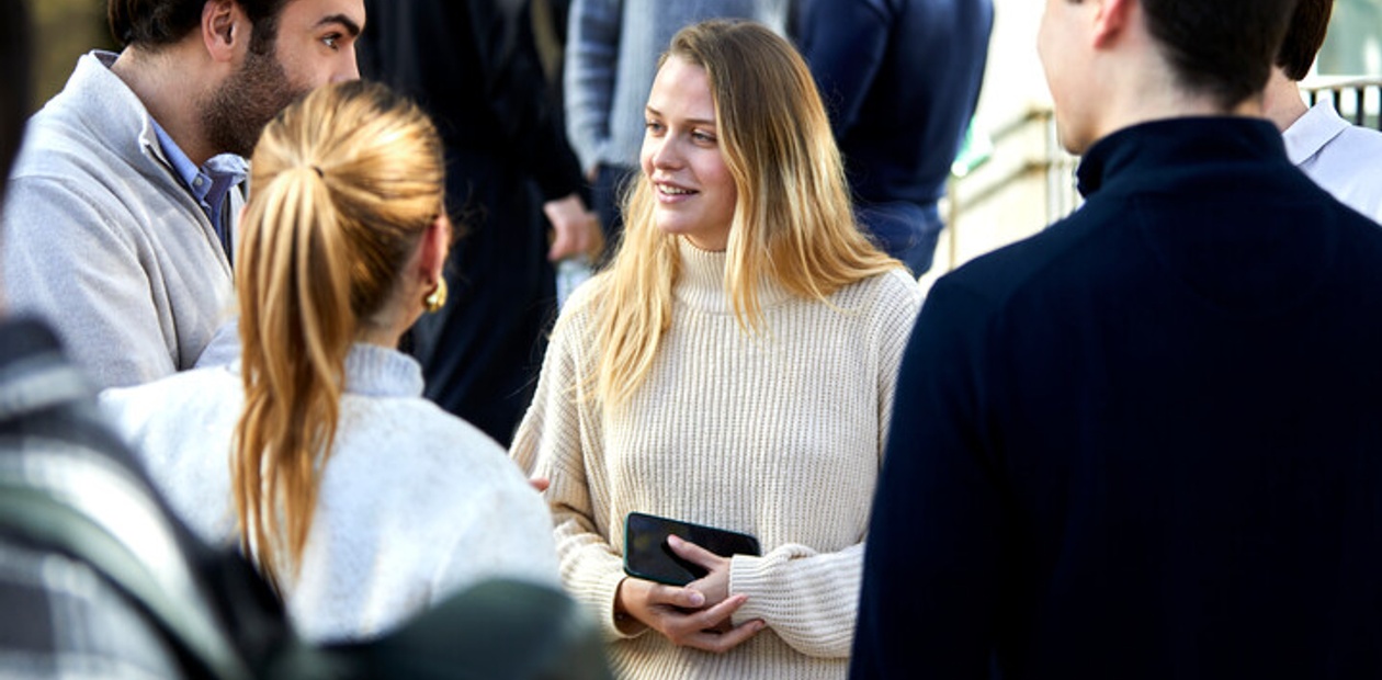 A group of young adults engaging in a friendly conversation outdoors.