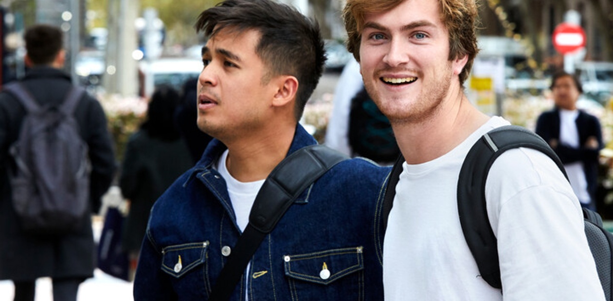 Two young men walking and smiling in an urban setting.