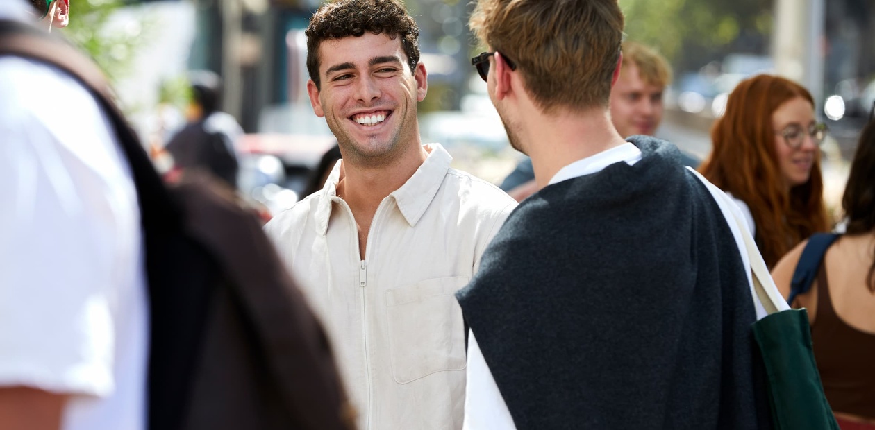 A group of young adults socializing outdoors on a sunny day.
