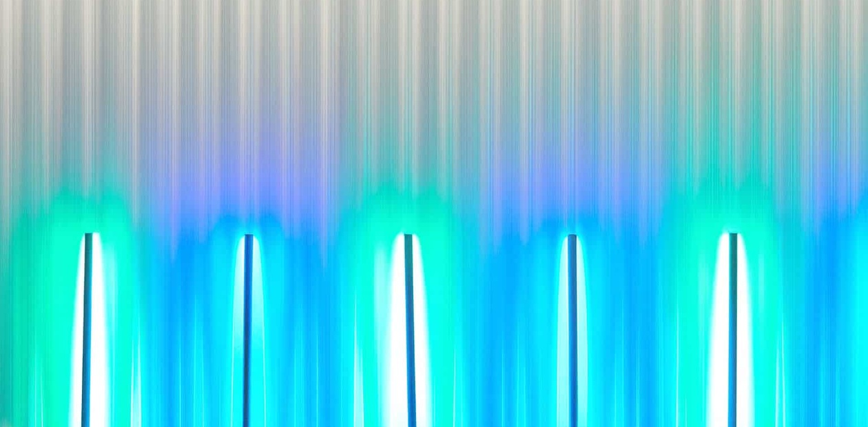 A futuristic setting with vertical lights casting a blue-green glow against a textured background.