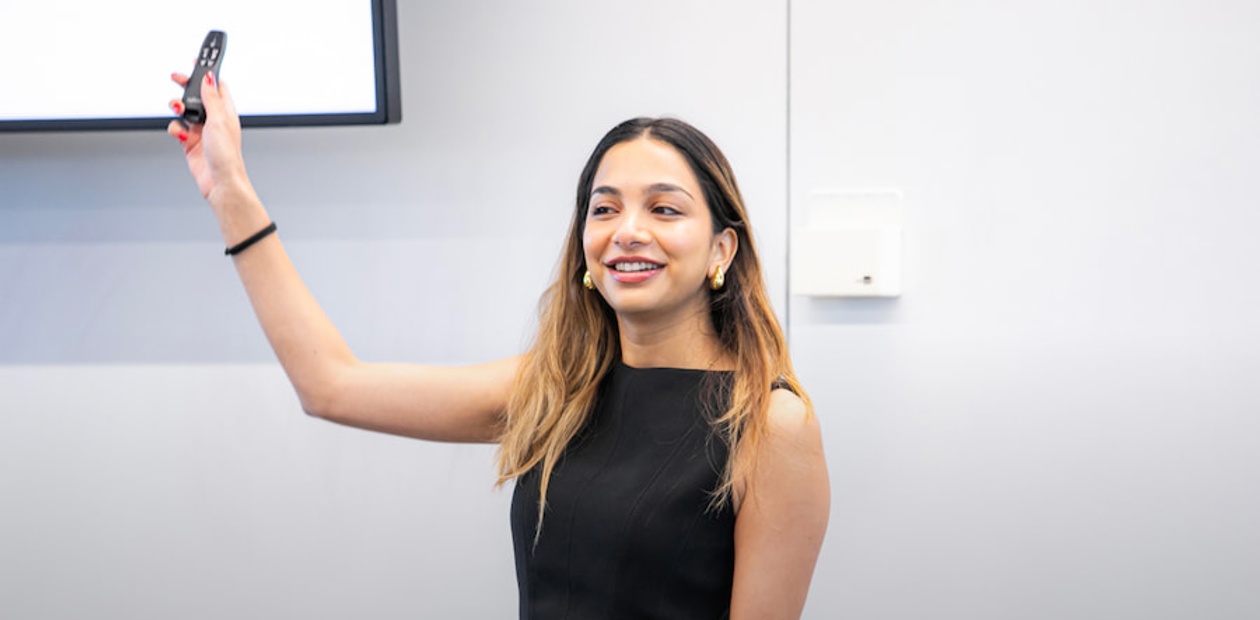 A young woman is giving a presentation while holding a remote control.