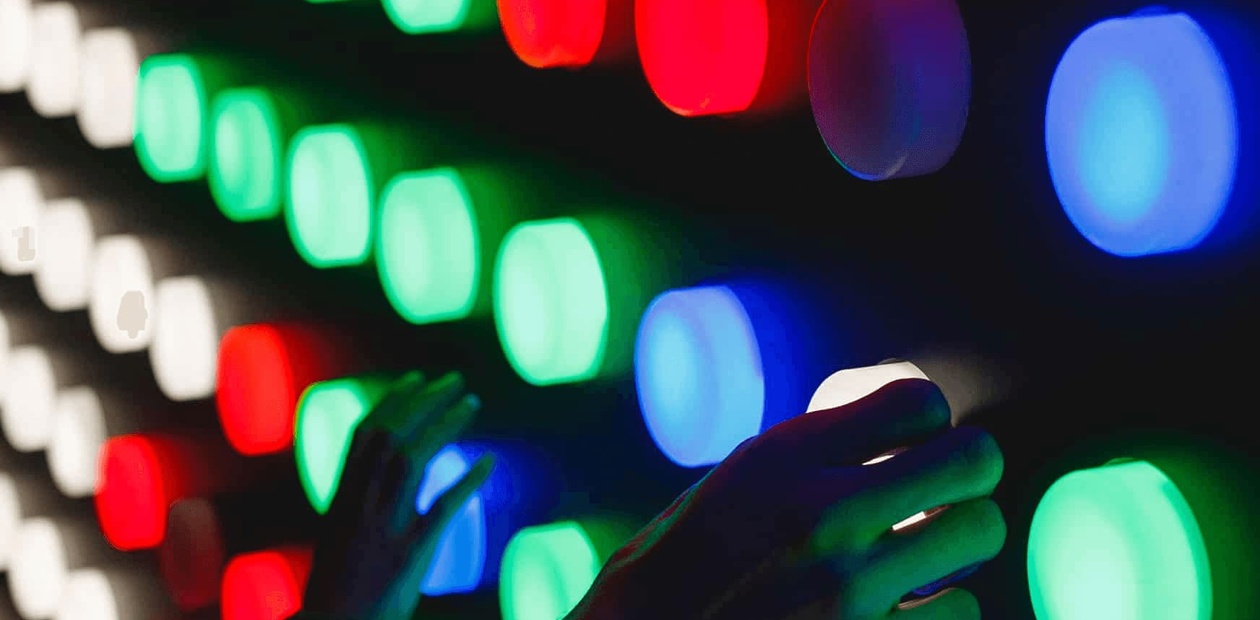 A person interacts with a colorful light installation featuring an array of illuminated spheres.