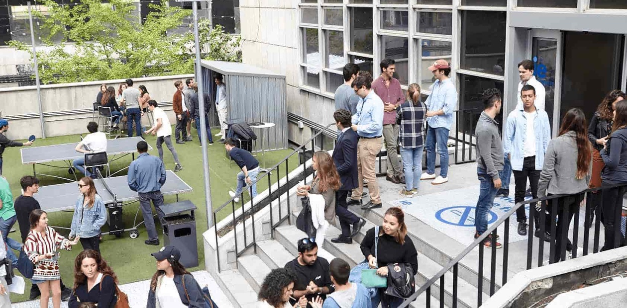 A group of people socializing in an outdoor area with modern architecture.