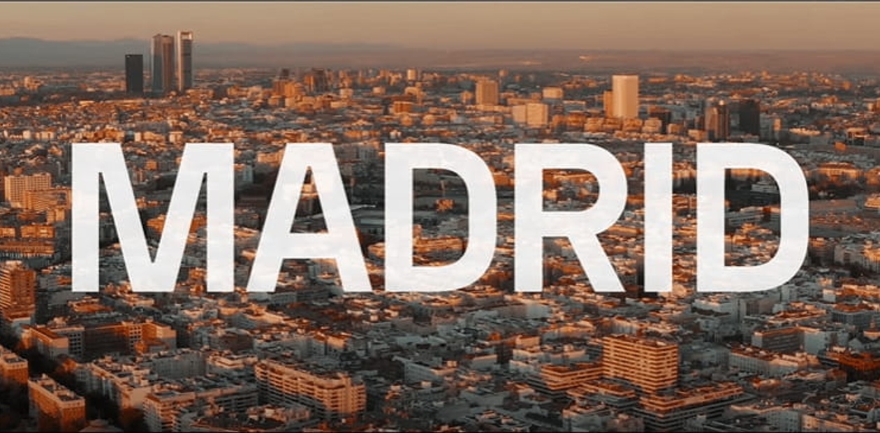 Aerial view of Madrid at sunset with the word 'MADRID' superimposed in large white letters.