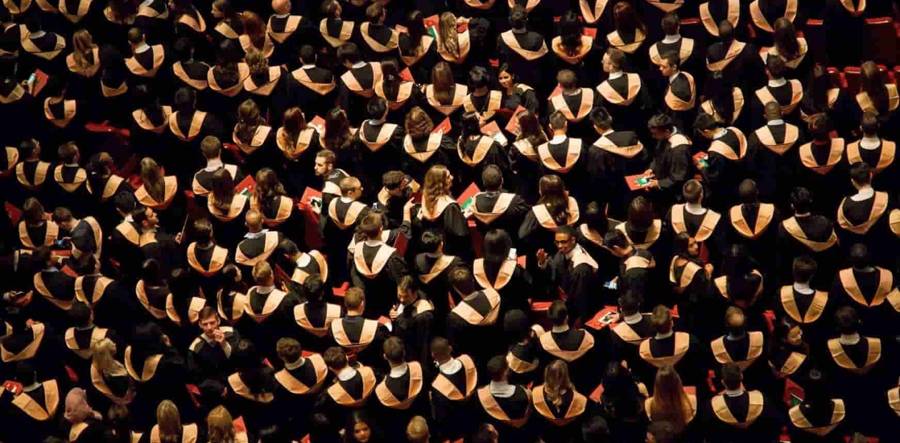 A large group of graduates wearing traditional caps and gowns during a graduation ceremony.