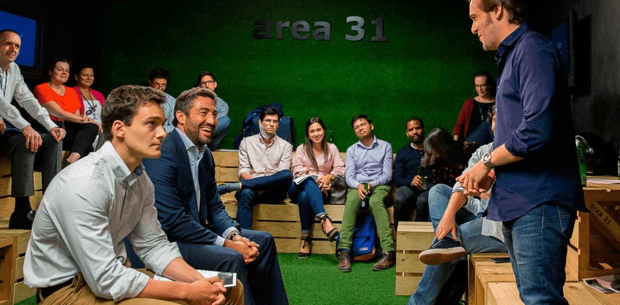 A group of people attentively listening to a speaker at an indoor seminar in a space labeled 'area 31'.