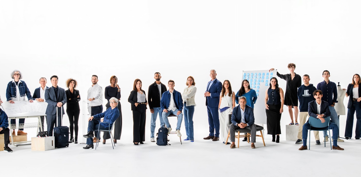 A diverse group of professionals standing and sitting together in a bright, minimalistic studio.