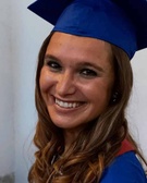 A smiling young woman wearing a blue graduation cap.