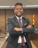 A confident man in a suit standing in a meeting room, smiling at the camera