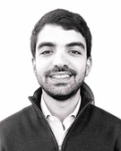 Black and white portrait of a smiling man with a beard and a zip-up jacket.