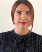 A woman with pink lipstick wearing a navy blue polka dot blouse.