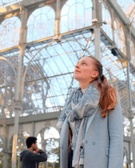 A woman admiring the architecture of a large glass structure, with a man in the background.