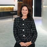 A woman in a stylish black and white jacket sits confidently in a modern interior.