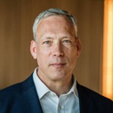 A portrait of a middle-aged man with a serious expression, wearing a suit and white shirt.