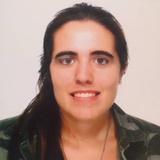 A portrait of a smiling woman with long dark hair, wearing a green jacket.