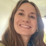 A smiling woman with long brown hair and a scarf looking at the camera.