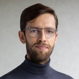 Portrait of a man with glasses wearing a turtleneck sweater.