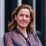 A woman smiling at the camera, dressed in a patterned blouse.