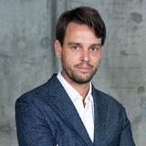 A professional portrait of a man in a business suit with a white shirt.