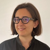 A smiling woman with glasses wearing a black shirt.