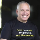 A smiling man wearing a black t-shirt with a motivational quote.